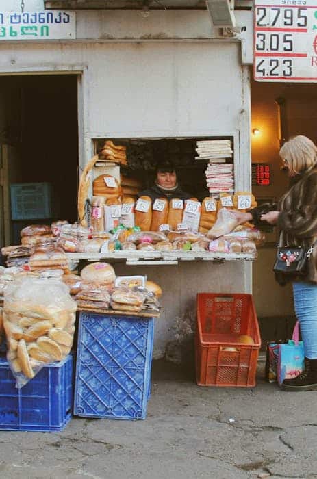A bustling bread market stall in Tbilisi, Georgia with a variety of fresh baked goods.