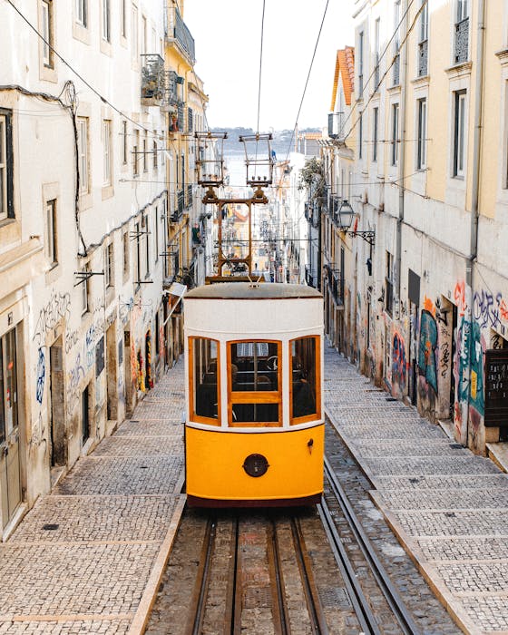 A classic yellow tram descends the graffiti-lined cobblestone streets of Lisbon, Portugal.