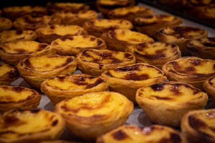 A close-up of freshly baked Pastel de Nata, iconic Portuguese custard tarts, in a Porto bakery.