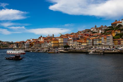 Beautiful panoramic view of Porto's riverside with colorful buildings and boats under a vibrant blue sky.