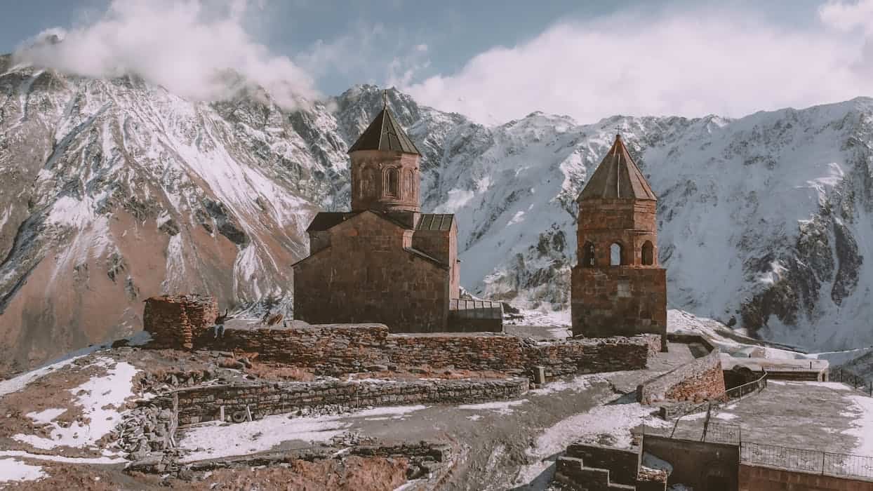 Historic Gergeti Trinity Church set against the stunning snowy Caucasus Mountains in Georgia.