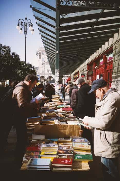 People browsing books at an outdoor market in Tbilisi, Georgia on a sunny day.