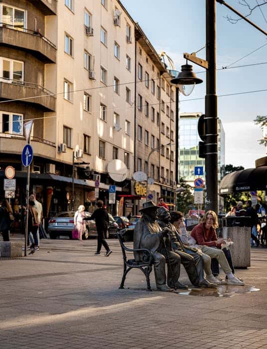 Vibrant downtown Sofia street scene with people around iconic bench statues in daylight.